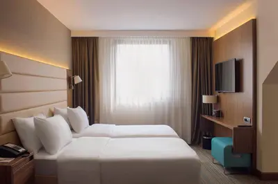 a hotel room with a white bed and a window at Courtyard by Marriott Belgrade City Center in Belgrade