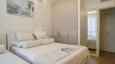 a white bedroom with a bed and a mirror at Exclusive Apartment in Belgrade