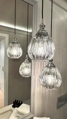 four glass lights hanging over a bathroom sink at DOM Boutique Apartments KING'S in Belgrade
