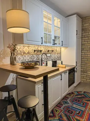 a kitchen with white cabinets and a counter with stools at Maison Dositej No20 in Belgrade
