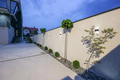 a fence with a palm tree next to a building at Apartment Cocosinella in Surčin