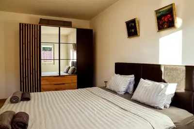 a bedroom with a bed with white sheets and a window at Kuca na dan - DIKAN in Ba°evac