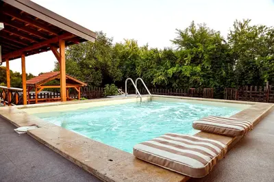 a swimming pool with two lounge chairs and a gazebo at Kuca na dan - DIKAN in Ba°evac
