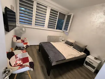 a bedroom with a bed and a chair and windows at Nina Urban Apartment-Novi Beograd in Belgrade