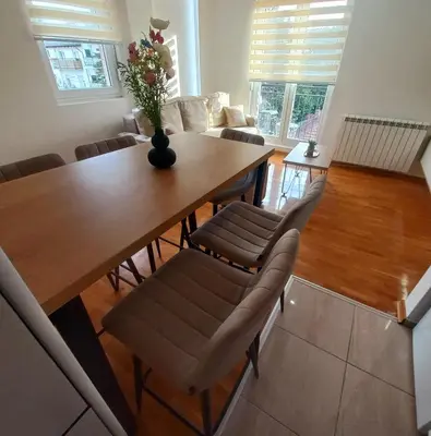 a dining room table with chairs and a vase with flowers at Royal lux apartman Beograd in Belgrade