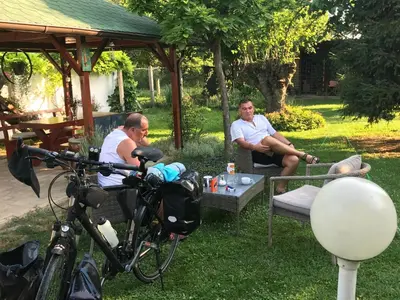 two men sitting in the grass under a gazebo at Santa Maria Apartment in Donji Kovilj