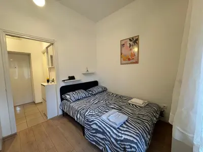 a small bedroom with a bed with a striped comforter at Heart Studio in Belgrade