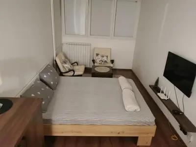 a small bedroom with a bed and a flat screen tv at Andrej 62 in Beograd