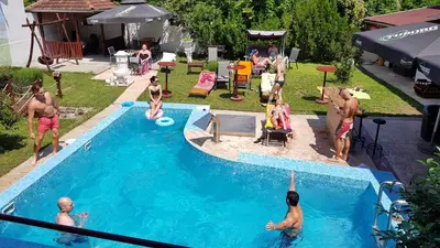 a group of people playing in a swimming pool at etno brvnara sa bazenom in Železnička Stanica Karlovački Vinogradi