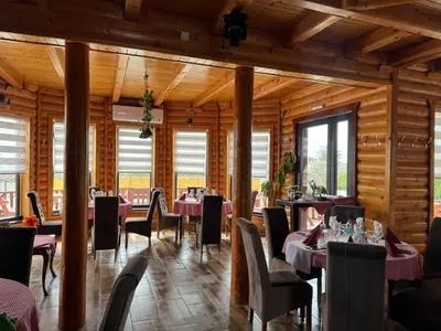 a dining room with tables and chairs and wooden walls at etno brvnara sa bazenom in Železnička Stanica Karlovački Vinogradi