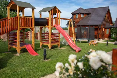 a playground with a slide in front of a cabin at etno brvnara sa bazenom in Železnička Stanica Karlovački Vinogradi