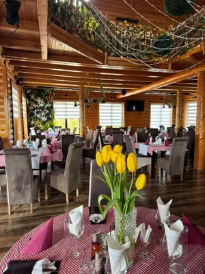 a dining room with tables and chairs with yellow flowers at etno brvnara sa bazenom in Železnička Stanica Karlovački Vinogradi