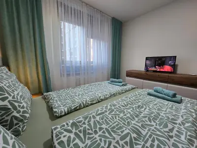a bedroom with two beds and a tv and a window at BW Quartet 302 deluxe apartments in Belgrade