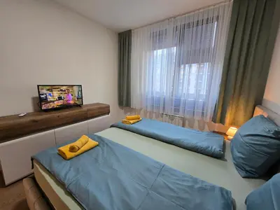 a room with two beds and a television and a window at BW Quartet 302 deluxe apartments in Belgrade
