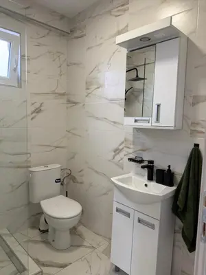a white bathroom with a toilet and a sink at Apartman na dan Pecinci in Pećinci