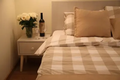 a bed with a vase of flowers and a bottle of wine at Bed&Breakfast kod Smilje in Belgrade