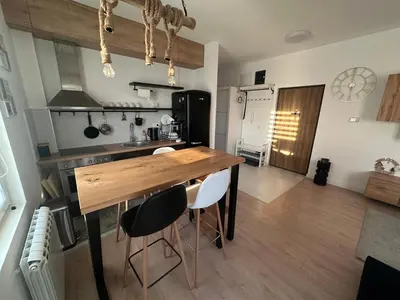 a kitchen with a wooden table and some chairs at Apartman 601 in Surčin