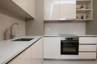 a kitchen with white cabinets and a sink at Jana BW apartman in Belgrade