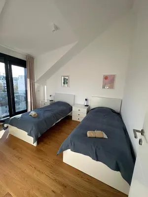 two beds in a bedroom with white walls and wood floors at Apartment 6 Belgrade in Belgrade