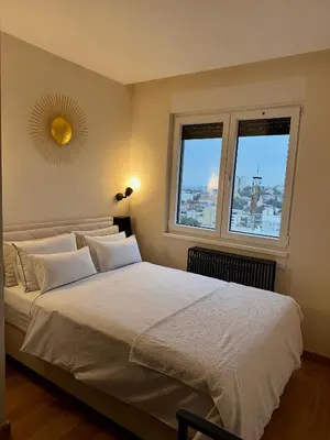 a bedroom with a large white bed with two windows at Cozy Luxury Studio with City View in Belgrade