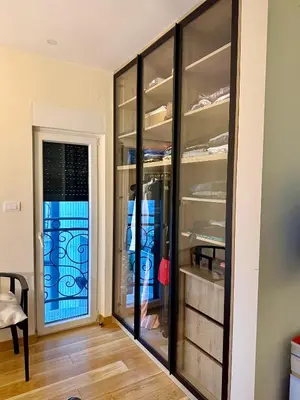 a walk in closet with glass cabinets and a door at Cozy Luxury Studio with City View in Belgrade