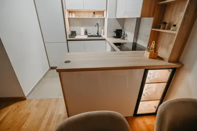 a small kitchen with a counter and some chairs at La Homa LUX in Pančevo