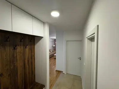 a hallway with white walls and a wooden door at La Homa LUX in Pančevo