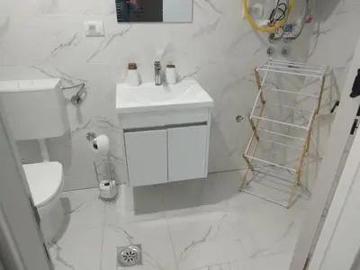 a white bathroom with a toilet and a sink at Apartman Lazar in Ruma