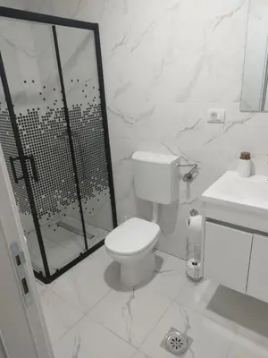a white bathroom with a toilet and a shower at Apartman Lazar in Ruma