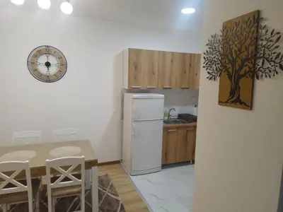 a kitchen with a refrigerator and a table and a clock at Apartman Lazar in Ruma