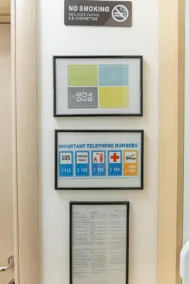 a no smoking sign on a wall with two framed pictures at lux Apartman lazar in Pančevo