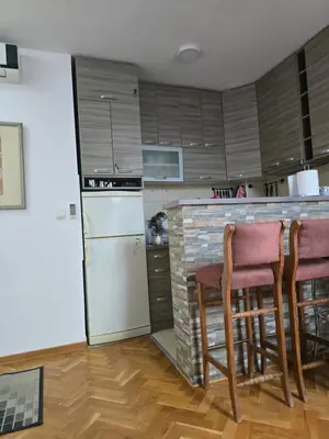 a kitchen with a counter with chairs and a refrigerator at Apartman Laki 56 in Kalugjerica