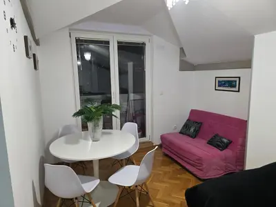 a living room with a white table and a pink couch at Apartman Laki 56 in Kalugjerica