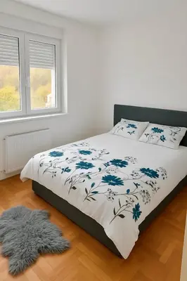 a bedroom with a bed with a blue and white blanket at Apartman Kalina in Belgrade
