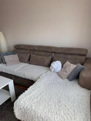a brown couch with pillows and a white rug at Kutak mira in Belgrade