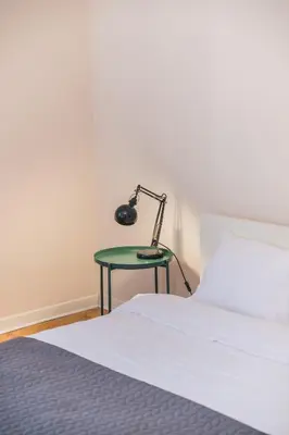 a bed with a green table with a lamp on it at Central Harmony Apartments 1 in Belgrade