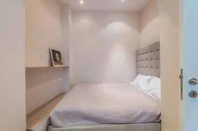 a small bedroom with a bed with white sheets at Central Harmony Apartments 2 in Belgrade