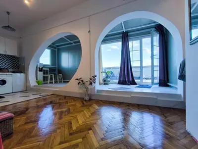 a living room with a wooden floor and large windows at apartment on top of the city in Belgrade