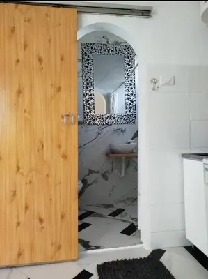 a bathroom with a wooden door and a mirror at apartment on top of the city in Belgrade