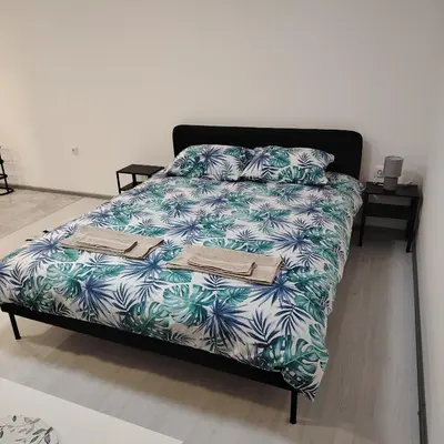 a bed with a blue and white comforter and pillows at Elena Airport Apartments in Surčin