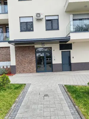 a white building with a blue door and grass at Lux Star Belgrade in Belgrade