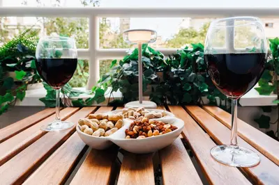 two glasses of wine and a bowl of food on a wooden table at Indigo Spirit with Terrace & Foosball Old Town in Belgrade