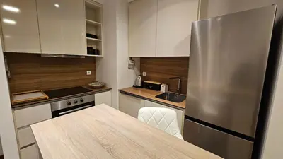 a kitchen with a stainless steel refrigerator and a table at BW Ivona Apartment Beograd na vodi in Belgrade