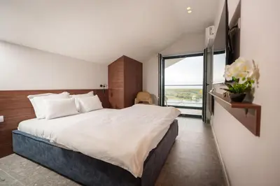 a bedroom with a large bed and a large window at Istros luxury house in Krčedin