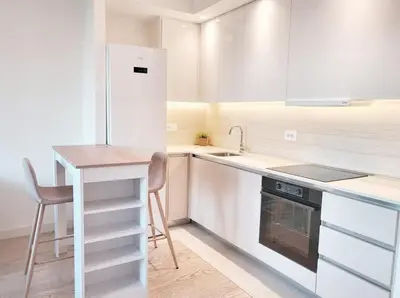 a white kitchen with a table and a refrigerator at Metropoliten - Aria Lux Apartments BW in Belgrade