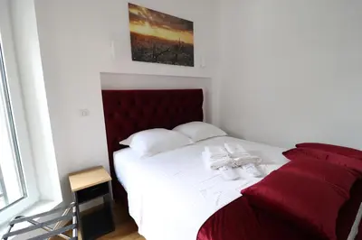 a bedroom with a white bed with a red headboard at Grandeur Slavija in Belgrade