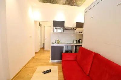 a living room with a red couch and a kitchen at Grandeur Slavija in Belgrade