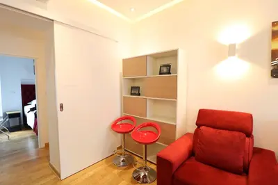 a living room with a red couch and a stool at Grandeur Slavija in Belgrade