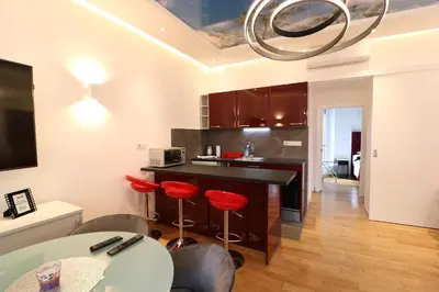 a kitchen with a bar with red stools in it at Grandeur Slavija in Belgrade