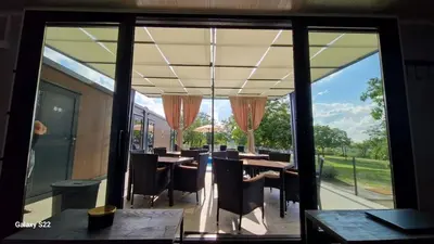 a restaurant with tables and chairs and large windows at Niki Hill in Železnička Stanica Karlovački Vinogradi